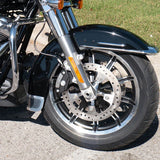 Close-up of motorcycle front wheel, disc brake, chrome fork, on concrete with grass background