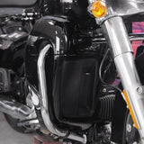 Close-up of black motorcycle engine guard, chrome crash bar, front fork and amber signal light