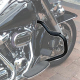 Black highway crash bar installed on chrome motorcycle with front wheel on brick pavement