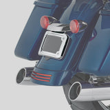 Blue touring motorcycle rear with chrome license plate frame, dual exhaust, red tail lights
