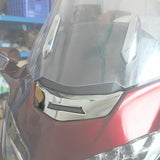 Close-up of a red motorcycle windshield with chrome accents in a workshop setting