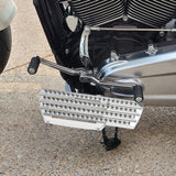 Motorcycle with chrome engine, custom silver floorboard, and foot controls on pavement