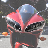Red sport motorcycle front view with aerodynamic windshield and dual headlights outdoors