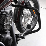 Close-up of motorcycle engine, chrome foot peg, and front wheel with crash bar