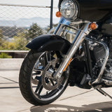 Front wheel and fork of a black touring motorcycle with chrome details outdoors