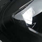 Close-up of a black automotive headlight with E13 marking and clear lens detail