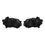 Pair of black automotive headlight housings with circular lens components on white background