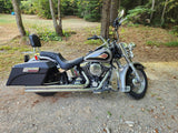 Silver Harley-Davidson motorcycle with saddlebags parked on gravel in a wooded area