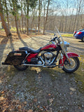 Red Harley-Davidson motorcycle parked outdoors on a gravel driveway with trees in background
