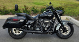 Black touring motorcycle with saddlebags parked on street, chrome engine, green grass background
