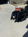 Black touring motorcycle with saddlebags and rolled blanket on driveway in sunlight