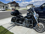 Black Harley-Davidson touring motorcycle with American flag parked in suburban driveway