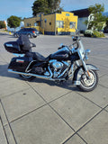Black Harley-Davidson touring motorcycle parked on city street near a yellow building