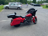 Red Harley-Davidson touring motorcycle parked in a lot with cars and trees in the background